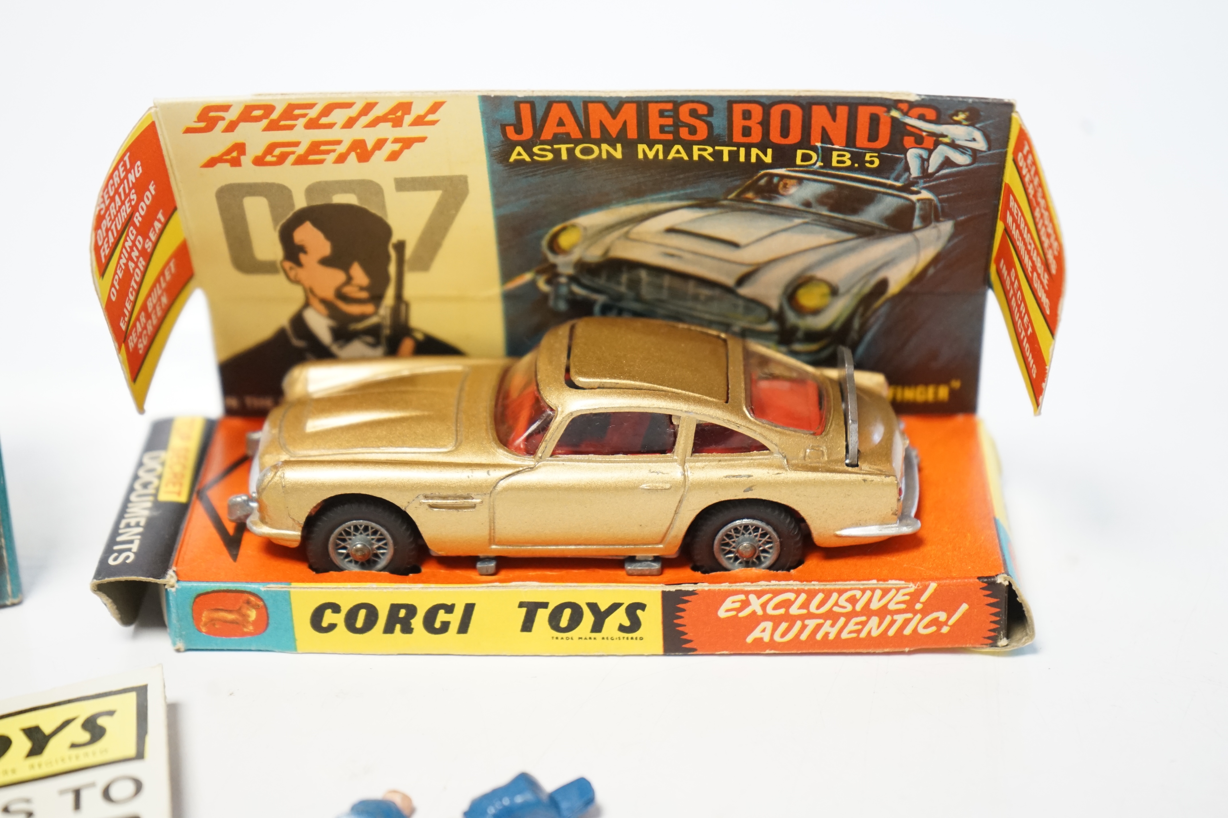 A boxed Corgi Toys James Bond 007 Aston Martin (261), a first issue example in gold finish, boxed with inner display stand, envelope for secret instructions, top-secret leaflet, sheet of two unused lapel stickers, and th